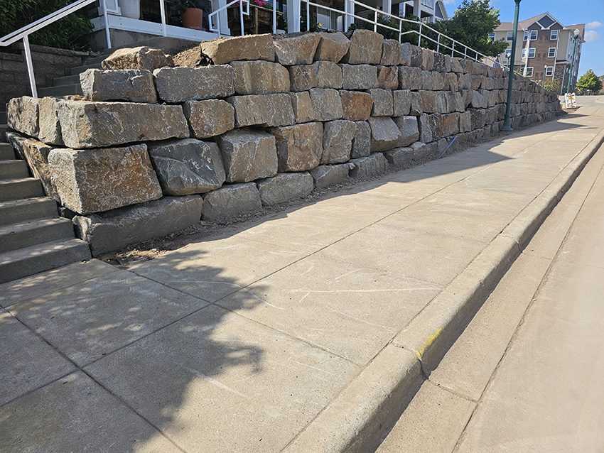 Commercial granite boulder retaining wall after replacement at a senior living property | Granite Companies MN