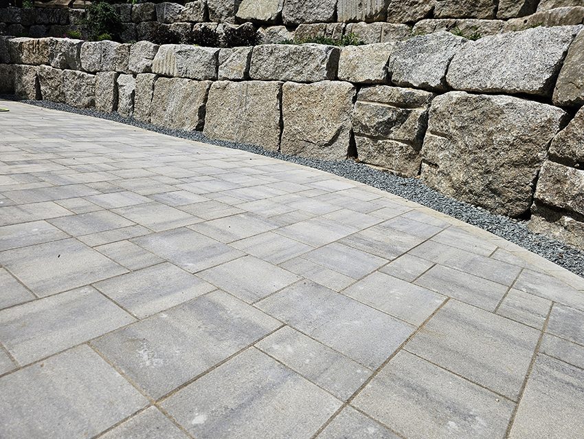Residential backyard granite boulder wall with paver patio after replacement | Granite Companies MN