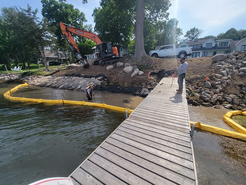 Boulder wall shoreline installation with excavator | Granite Companies MN